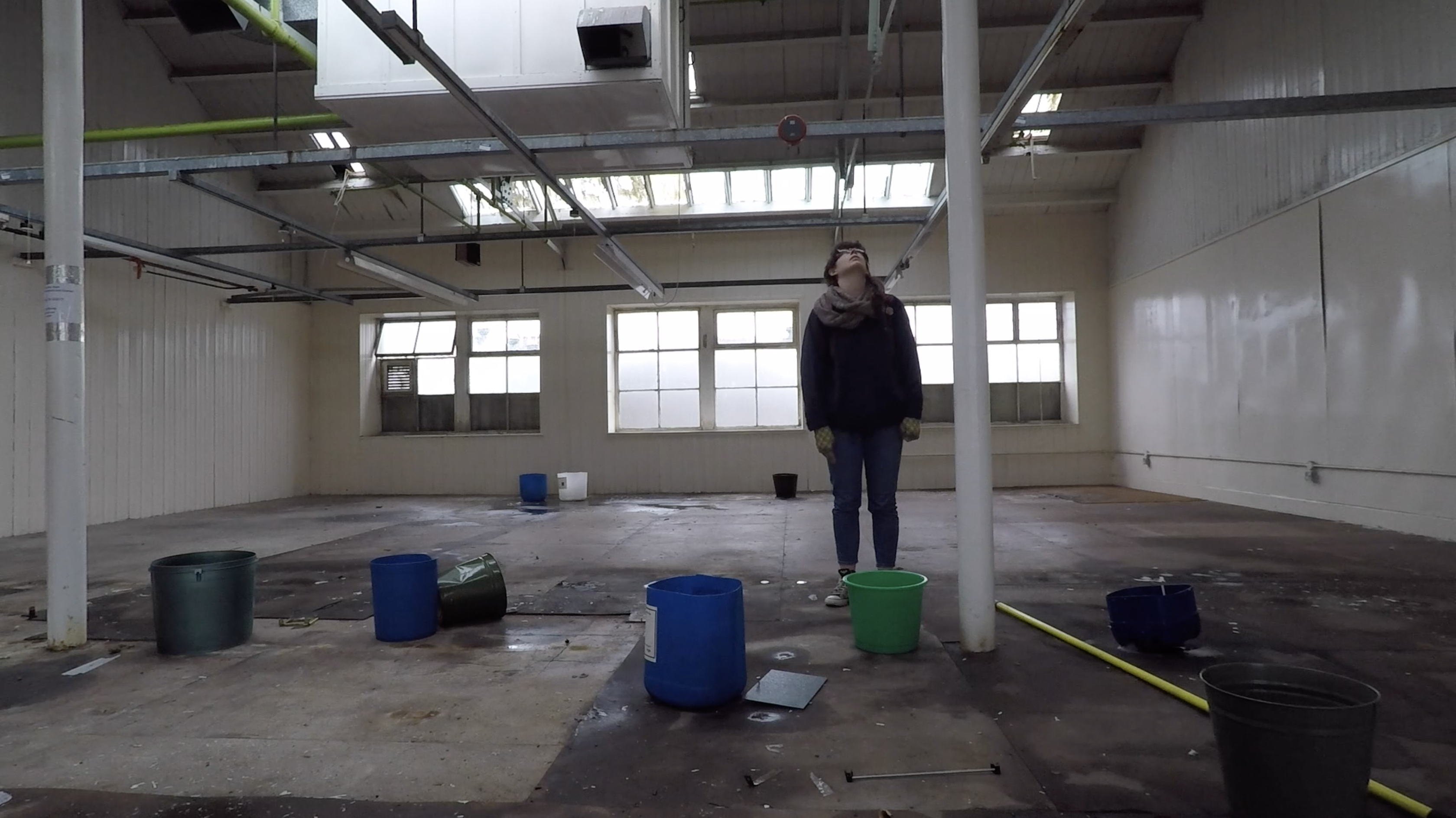 Woman stares at the ceiling in a room with buckets on the floor