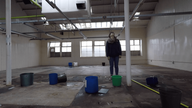 Woman stares at the ceiling in a room with buckets on the floor