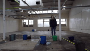 Woman stares at the ceiling in a room with buckets on the floor