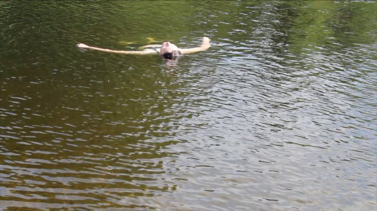 A person floats in a gently flowing river