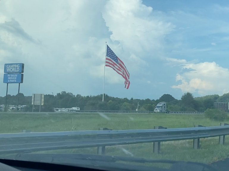 Seen from a car on a highway, a very large USA flag flies